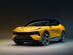 Onder studioverlichting wordt een felgeel-zwarte Lotus Eletre-sportwagen tentoongesteld, die het strakke ontwerp en de hoekige lijnen benadrukt.
