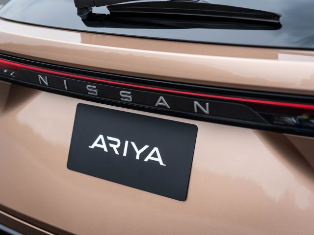 Close-up van de achterkant van de Nissan Ariya, een 100% elektrische crossover, met het Nissan-logo en het Ariya-naamplaatje op de kofferbak.