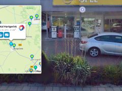 Buitenkant van een benzinestation met een kaart-overlay met brandstofprijzen en locaties, met 'goedkoop benzine' en een zilveren auto die ervoor geparkeerd staat.