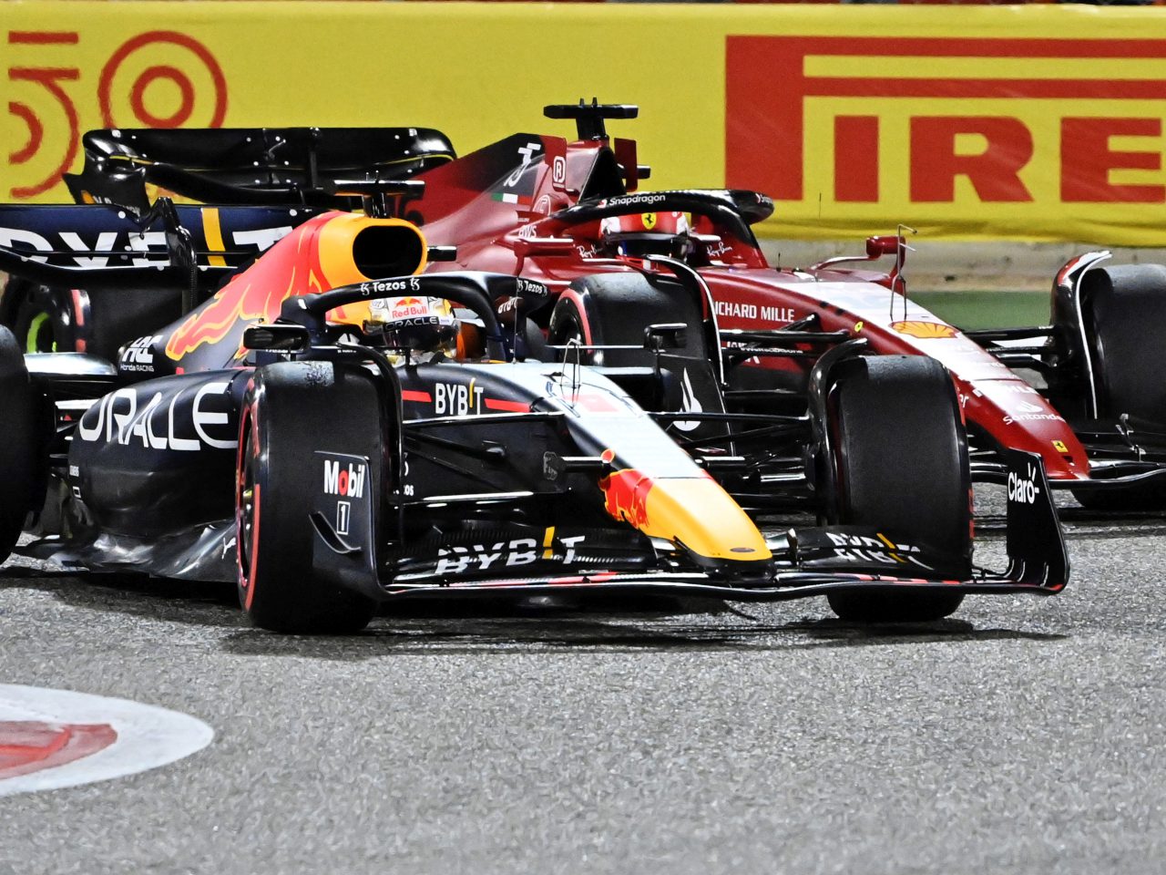 Twee Formule 1-auto's van Oracle Red Bull Racing en Scuderia Ferrari racen zij aan zij op een circuit tijdens de kwalificatie Australië, met Pirelli-bewegwijzering op de achtergrond.