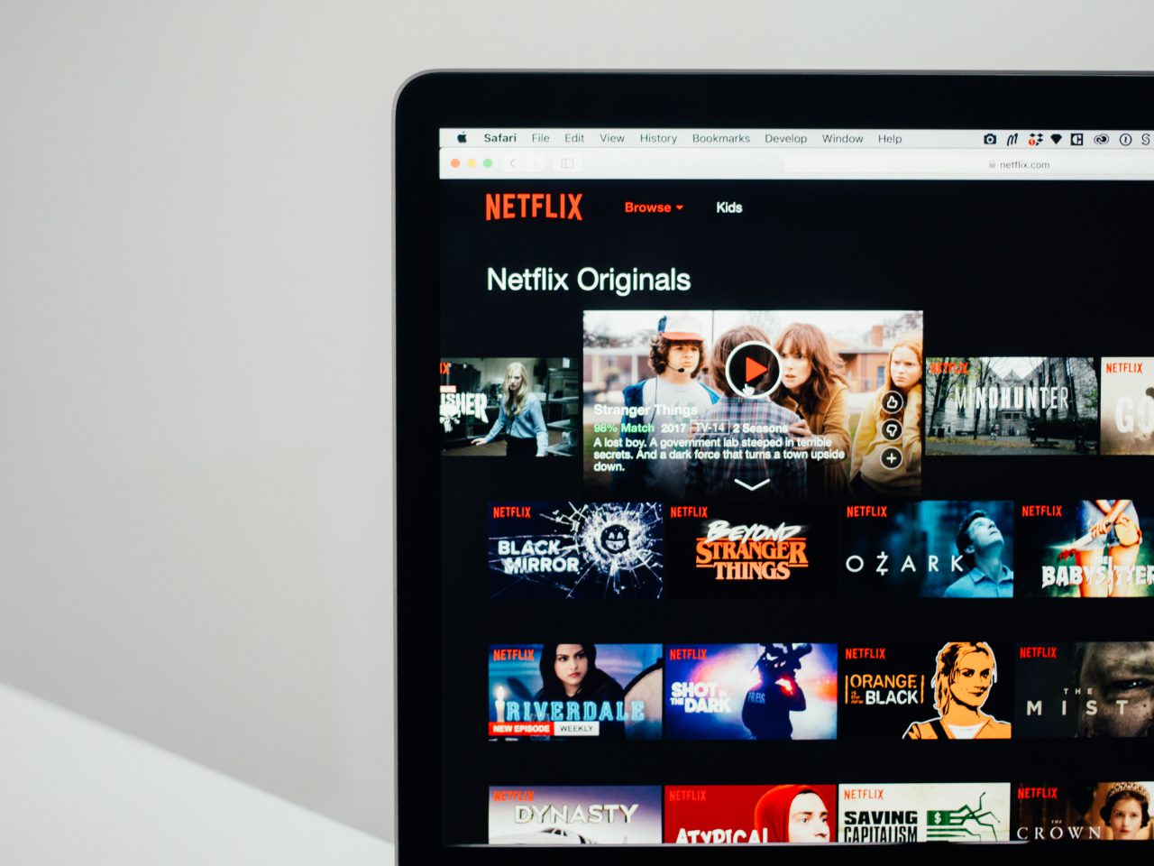 Een laptop die de Netflix-startpagina weergeeft met verschillende shows en films, waaronder Netflix Originals en beroemde auto's in films, zichtbaar op het scherm.