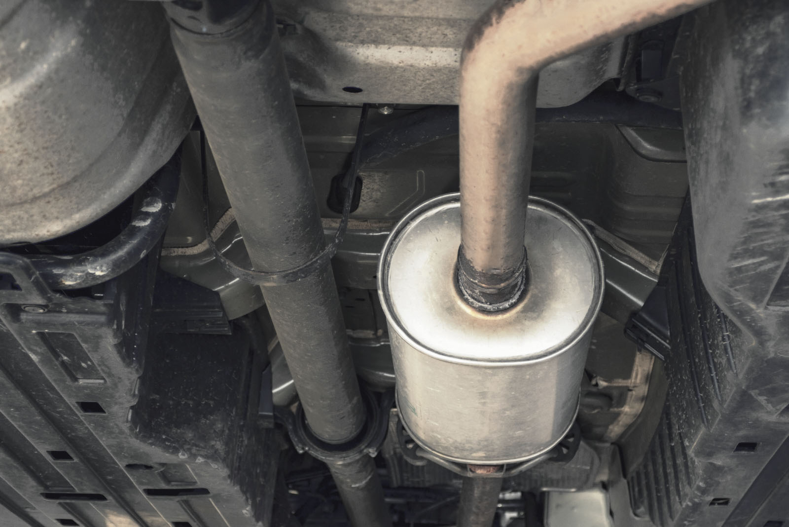 Een weergave van het uitlaatsysteem van een voertuig van onderaf, met pijpen en een uitlaatdemper, ideaal voor mensen die het proces van het verwijderen van de middendemper willen begrijpen.