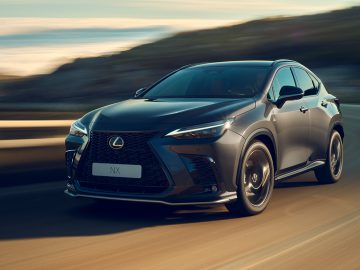 Een zwarte Lexus NX-auto rijdt op een mooie, bochtige weg met een onscherpe achtergrond, wat beweging aangeeft – een gelegenheid om te zoeken en nooit te vergeten.