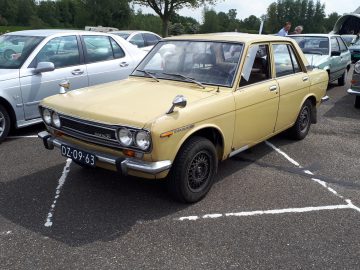 Een beige vintage auto met kenteken "DZ-09-63", een embleem van de tijdloze kwaliteit van Elk Merk Waardig, staat geparkeerd op een drukke parkeerplaats, omringd door andere voertuigen.