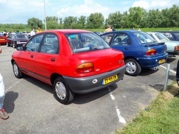 Een parkeerplaats met twee compacte hatchback-auto's, een rode en een blauwe, naast elkaar geparkeerd, waarvan de levendige kleuren de scène elk merkwaardig maken.