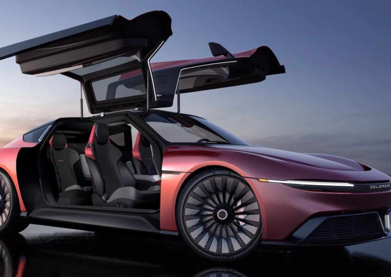 Een slanke, rode DeLorean EV Alpha5 met open vleugeldeuren, met een modern interieur met kuipstoelen, geparkeerd op een reflecterend oppervlak met een zonsondergang op de achtergrond.
