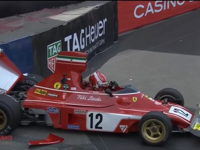 Een rode Formule 1-auto met het nummer 12 botst tijdens een race tegen een barrière, met zichtbare schade aan de achtervleugel. Charles Leclerc zit nog in het voertuig.