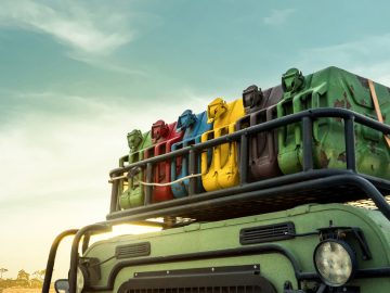 Dak van een groen voertuig met zes kleurrijke jerrycans gemonteerd op een imperiaal tegen een zonsondergang op de achtergrond, wat de sfeer van benzinereizen door het pittoreske Deutschland oproept.