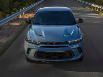 Een vooraanzicht van een blauwe Tonale die over een weg rijdt met aan beide zijden vangrails.