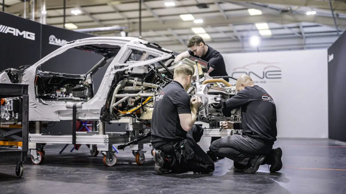 In een goed verlichte werkplaats assembleren technici een hoogwaardig Mercedes-AMG-voertuigchassis, waarbij ze zich nauwgezet concentreren op verschillende componenten.