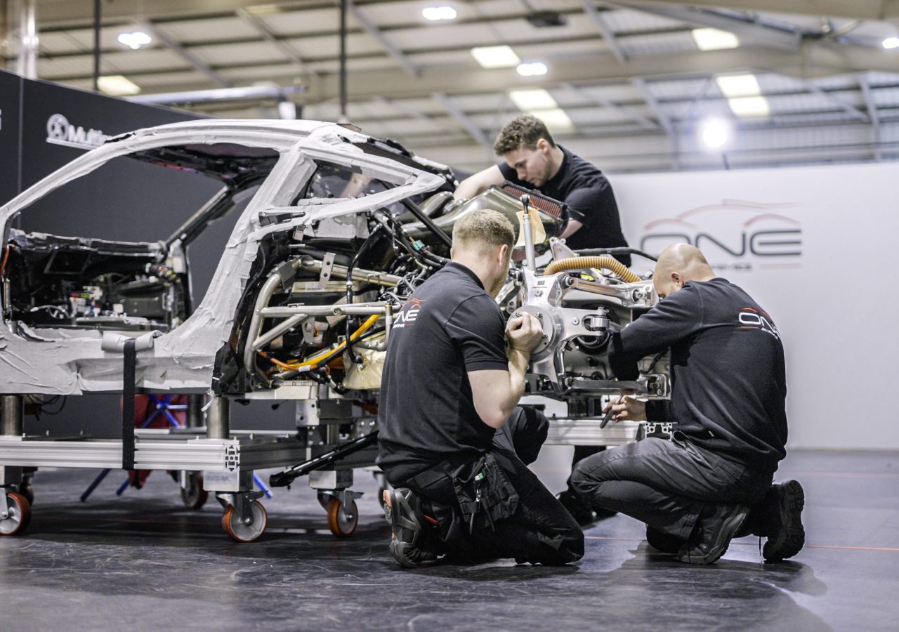 In een goed verlichte werkplaats assembleren technici een hoogwaardig Mercedes-AMG-voertuigchassis, waarbij ze zich nauwgezet concentreren op verschillende componenten.