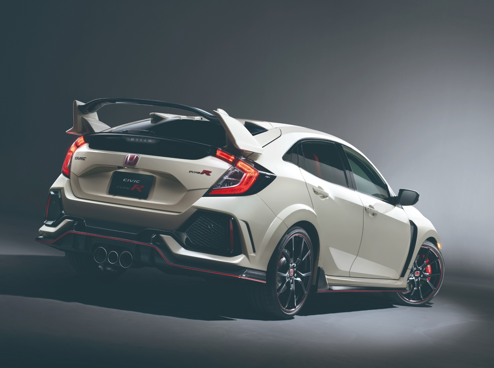 Achteraanzicht van een witte Civic Type R-sportwagen met prominente achterspoiler, drievoudige uitlaatpijpen en zwarte wielen, gemarkeerd tegen een grijze achtergrond.