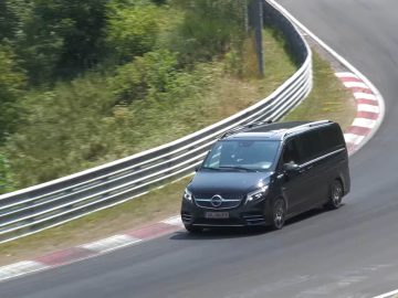 Een strak zwart Mercedes-Benz busje dat over een gebogen racecircuit rijdt met groen op de achtergrond. Het voertuig lijkt met hoge snelheid de bocht te nemen.