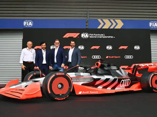 Vier mannen staan naast een Audi Formule 1-raceauto voor een achtergrond met FIA- en Audi-logo's.