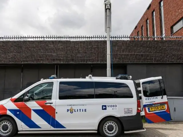 Voor een bakstenen gebouw staat een Nederlands politiebusje met de opschriften