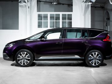 Een paarse, moderne zespersoonsauto SUV staat binnen geparkeerd voor witte muren en een raam.