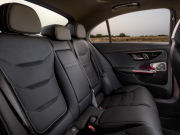 Het interieur van de achterbank van de Mercedes-AMG C 63 S E Performance is voorzien van zwartleren stoelen met gele stiksels, hoofdsteunen en een strak deurpaneel versierd met bedieningsknoppen.