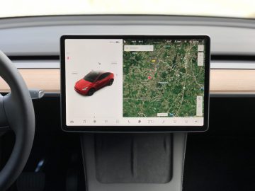 Een autodashboardscherm, of "schermen", toont een kaart aan de rechterkant en een autostatusdisplay aan de linkerkant in een minimalistische dashboardopstelling.