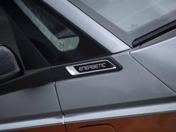 Close-up van het zijdetail van een Volkswagen Multivan met het woord "Energetisch" op de bekleding bij het zijraam en de deur.