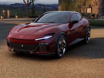 Een Ferrari Purosangue staat geparkeerd op een verhard oppervlak met schilderachtige heuvels en een rustiek gebouw op de achtergrond.