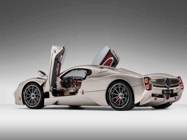 Een slanke zilveren Pagani Utopia-sportwagen met een aerodynamisch ontwerp, met open vleugeldeuren en een rood interieur. De auto wordt weergegeven tegen een effen witte achtergrond.