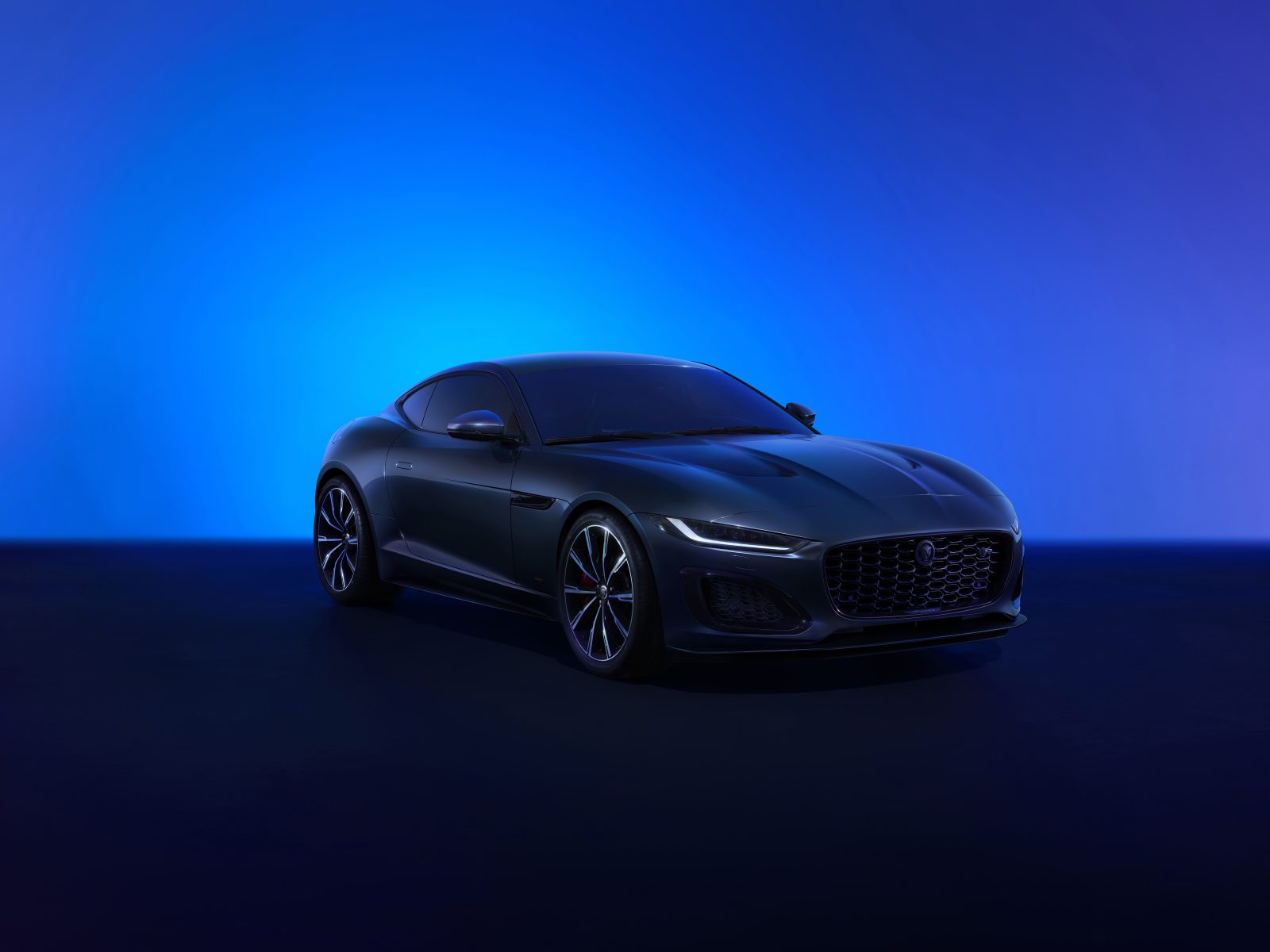 Een strakke zwarte Jaguar F-Type 75 sportwagen wordt tentoongesteld tegen een gradiëntblauwe achtergrond.