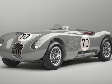 Een zilveren Jaguar C-Type vintage raceauto met het nummer 70 op de motorkap en zijkanten wordt weergegeven tegen een effen achtergrond. De auto is voorzien van klassieke spaakwielen en een open ontwerp.