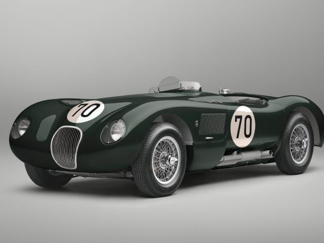 Een vintage Jaguar C-Type racewagen met het nummer 70 op de carrosserie, donkergroen geverfd en op een effen grijze achtergrond.