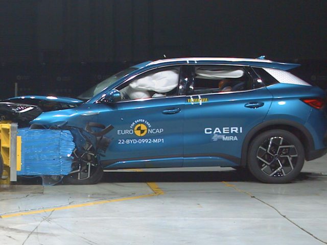 Een blauwe BYD Atto 3 SUV die een frontale crashtest met geactiveerde airbags ondergaat, uitgevoerd door Euro NCAP, in een gecontroleerde omgeving.