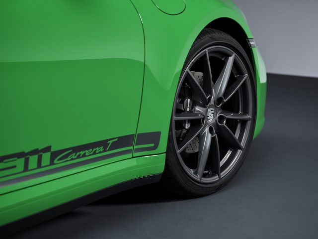 Close-up van de achterkant van een groene Porsche 911 Carrera T-sportwagen met het grijze wiel en het "911 Carrera T"-embleem op het onderste zijpaneel.