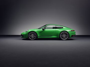 Een Porsche 911 Carrera T in levendig groen wordt in profiel getoond tegen een grijze achtergrond.