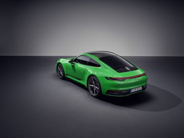 Een groene Porsche 911 Carrera T staat geparkeerd in een slecht verlichte ruimte, met duidelijk zicht op de achterkant en zijkant.