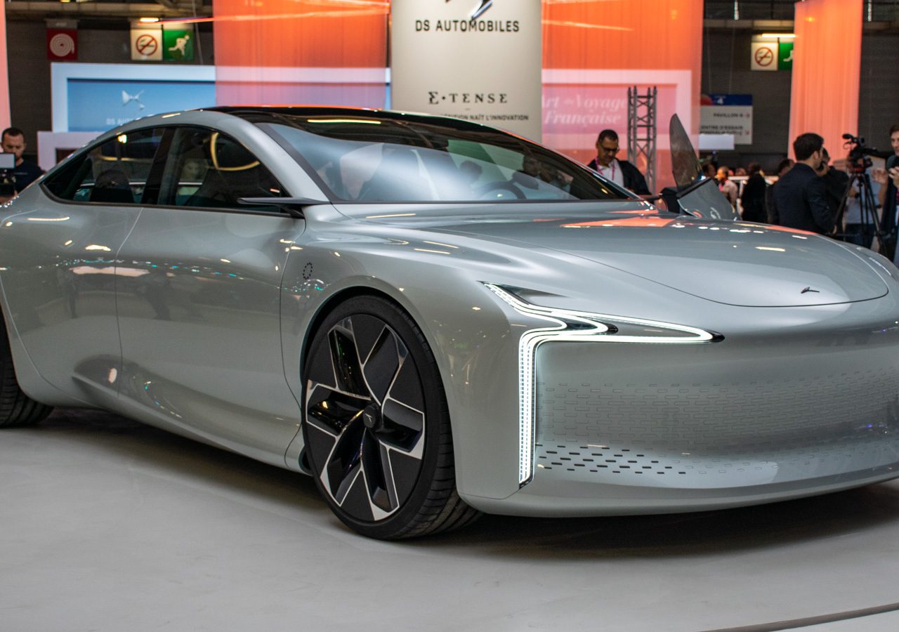 Futuristische zilveren conceptauto met strak ontwerp en grote zwarte lichtmetalen velgen tentoongesteld op de Autosalon Parijs 2022, omringd door mensen en felle verlichting.