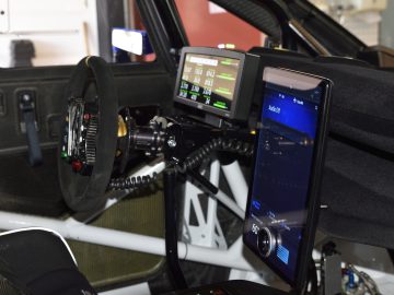 Interieur van een Ford E-Transit-racewagen met een stuur, digitale displays en geavanceerde besturingssystemen.