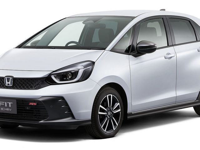 Een witte compacte Honda Fit e:HEV-auto met een zwarte grille en lichtmetalen velgen, gezien vanuit de linkervoorhoek, die doet denken aan de sportieve Honda Jazz RS.