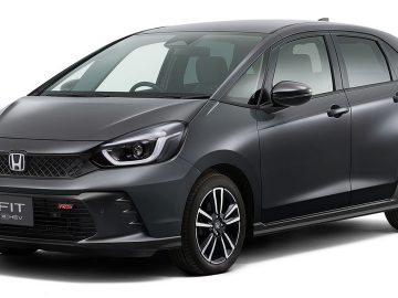 Een grijze Honda Fit e:HEV RS hatchback, in sommige markten ook wel de Honda Jazz RS genoemd, staat geparkeerd, gezien vanaf de linkerkant. Het voertuig heeft strakke lijnen, een compact ontwerp en moderne LED-koplampen.