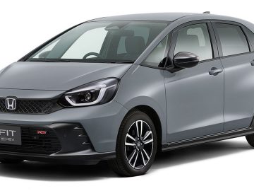 Er staat een zilveren Honda Jazz RS e:HEV hatchback geparkeerd, voorzien van een modern ontwerp met zwarte lichtmetalen velgen en een strakke grille.