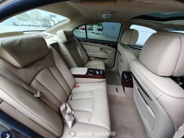 Het interieur van de Ssangyong Chairman CW700 straalt weelde uit met zijn beige luxe bekleding, achterbank die ultiem comfort bieden, een middenconsole uitgerust met bekerhouders voor gemak, en elegante houten sierdetails.