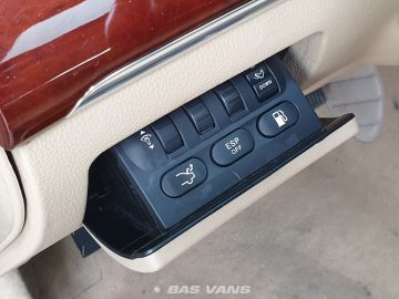 Close-up van het bedieningspaneel van een Ssangyong Chairman CW700 met knoppen voor het aanpassen van de stoelpositie, het uitschakelen van ESP en het openen van de tankdop. Het paneel is gevat in een beige lederen dashboard.