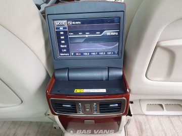 Het scherm op de achterconsole van een Ssangyong Chairman CW700 met de radio-instellingen, gepositioneerd boven de ventilatieopeningen van de airconditioning en bedieningsknoppen, met daaronder een vloerbedekking.