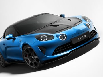 Een blauwe Alpine A110 R-sportwagen met een zwarte koolstofvezel motorkap en een aerodynamisch ontwerp, weergegeven vanuit de linkervoorhoek, legt de essentie van precisietechniek vast.