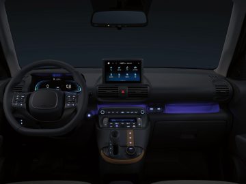 Modern auto-interieur met een dashboard met een verlicht bedieningspaneel, digitale displays, een stuur met ingebouwde bedieningselementen en sfeerverlichting, vergelijkbaar met het verfijnde ontwerp van de Hyundai Casper.