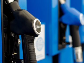 Close-up van een zwarte hendel van de dieselpomp bij een benzinestation, waarbij het probleem van het dieseltekort wordt benadrukt, met een andere hendel van de brandstofpomp zichtbaar op de onscherpe achtergrond.