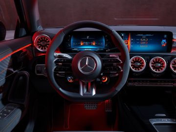 Binnenaanzicht van het moderne dashboard van een Mercedes-Benz A-Klasse met een stuur met het iconische Mercedes-Benz-logo, digitale displays en verlichte ventilatieopeningen.