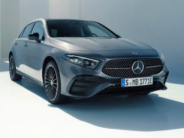 Een grijze Mercedes-Benz A-Klasse hatchback geparkeerd op een gladde, lichtgekleurde ondergrond. Op het kenteken staat "S MB 1771E".