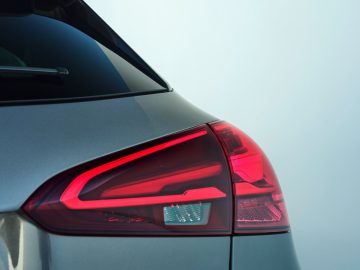 Close-up van het achterlicht van een Mercedes-Benz A-Klasse, met een strak, modern ontwerp met een rood en wit kleurenschema tegen een lichtblauwe achtergrond.