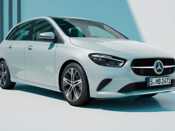 Een strakke witte Mercedes-Benz B-Klasse, die doet denken aan de stijlvolle A-Klasse, staat geparkeerd in een helder verlichte ruimte met een kentekenplaat met de tekst ‘S MB 2472.