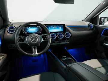 Een modern auto-interieur met een Mercedes-Benz A-Klasse-logo op het stuur, digitale displaypanelen, blauwe accentverlichting en een strak dashboardontwerp.