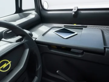 Interieur van een Opel Rocks-e met een dashboard met een tablet op de middenconsole. Het stuur bevindt zich aan de linkerkant van de afbeelding. Het interieur oogt modern en minimalistisch.