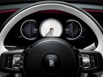 Close-up van het stuur van een Rolls-Royce Spectre en het digitale dashboarddisplay met de snelheidsmeter, brandstofmeter en andere bedieningselementen.